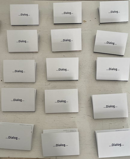 Es liegen fünfzehn Schilder mit der Aufschrift „Dialog“ auf einem Tisch.