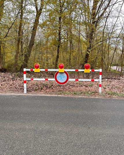 Eine rotweiße Schranke vor einem Wald. An der Schranke hängt ein Nicht Befahren Schild, auch wenn es dahinter gar keinen Weg gibt.