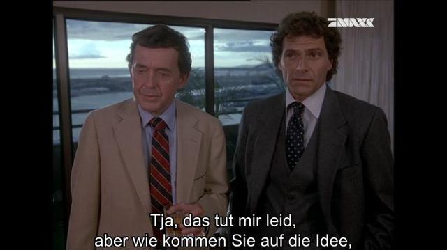 Description: The image shows two men in suits and ties standing next to each other in front of a window, with a curtain on the right side and text at the bottom. Through the window, we can see trees, water, buildings, and the sky.

Disclaimer: This image description was automatically generated and may not be entirely accurate.