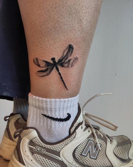 Dragonfly tattoo above the sock line