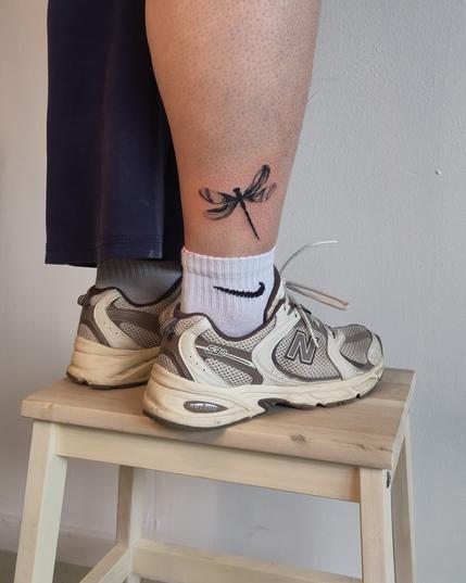 Dragonfly tattoo above the sock line