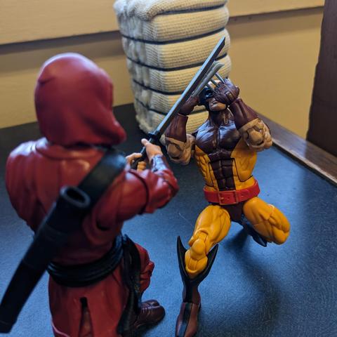 A Marvel Legends Wolverine in the yellow and brown suit crouched down blocking the sword of a Hand Ninja with both sets of claws