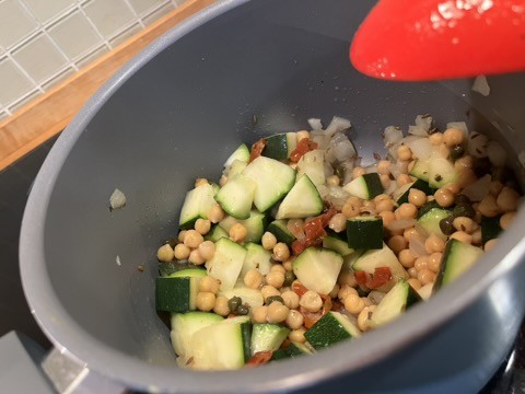 las verduras descritas, en una hoya gris siendo cocinadas
