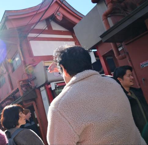 In a busy lane a man is shielding his eyes from the bright sun.