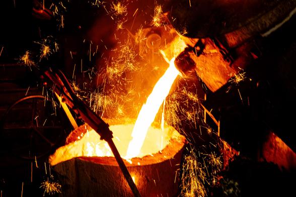 Molten metal being poured into a crucible; sparks flying.