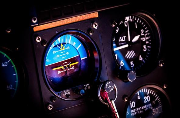 This image shows a section of an aircraft's cockpit instrument panel. It includes:

1. An attitude indicator (artificial horizon), which displays the aircraft's orientation relative to the horizon.
2. An altimeter, indicating the aircraft's altitude.
3. A vertical speed indicator, showing the rate of climb or descent.

These instruments are essential for pilots to maintain proper control and navigation of the aircraft.