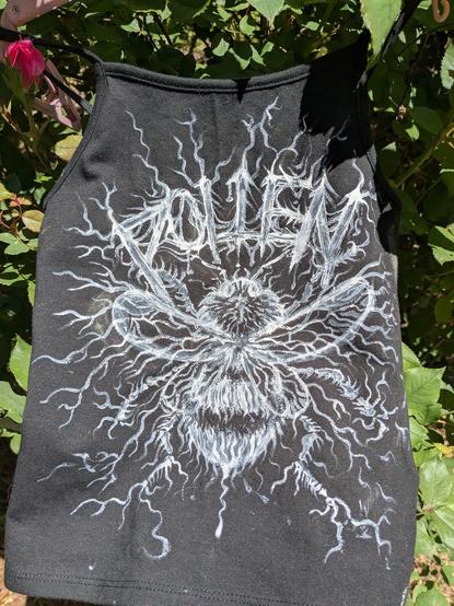A black cropped tank top with Pollen written on it in a gothic white font, and a furry honey bee painted on it.  It is on an XS teeny tiny crop top that would fit tiny people and children.