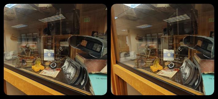 A display case filled with stereoscopes, ViewMasters, 3D cameras, etc. There's a lot of reflection on the glass.