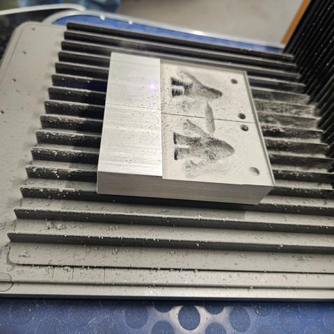 the two completed mold halves still on the laser bed and covered in aluminum powder that the laser dislodged from the aluminum block.
