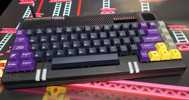 a wedge shaped computer where the computer internals are inside the keyboard. it's a black case F256K2 from Foenix Retro System, with mostly black keycaps for the letters and numbers, but with purple special keys (shift, enter, etc.) and yellow ones for the arrow keys.