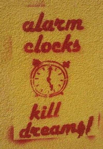 Spray painted stencil showing a clock face and the words "Alarm clocks kill dreams!"