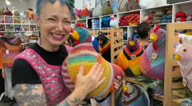 Woman in yarn store holding knitted chicken