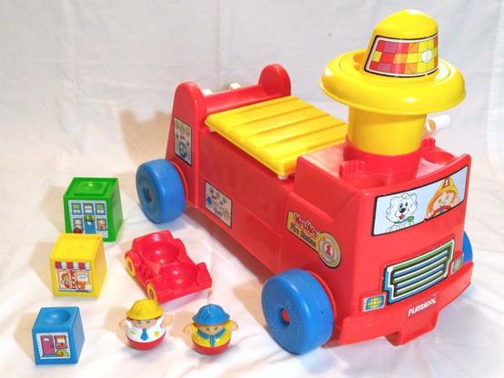 Weebles Fire Station playset from late 1980s. Includes ride-on toy shaped like a fire engine that converts to a fire station, a subcompact fire engine with two bucket seats, three stackable blocks styled as buildings, and firefighter and fire chief figures.