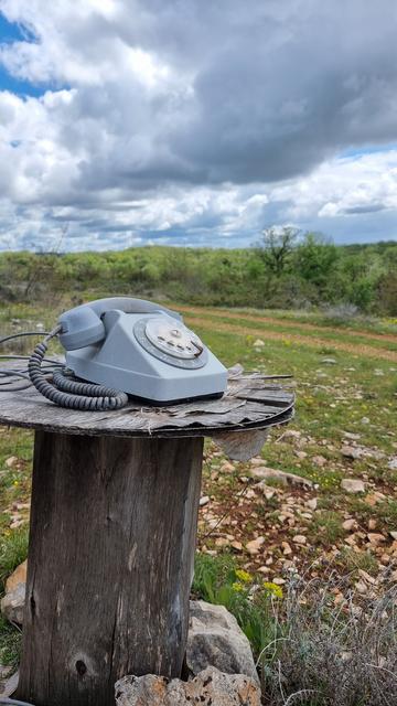 Sur le chemin de compostelle , vers Gréalou, un téléphone à cadran est posé sur une bobine de chantier,on voit au loin le causse du Quercy sous un ciel plombé et orageux