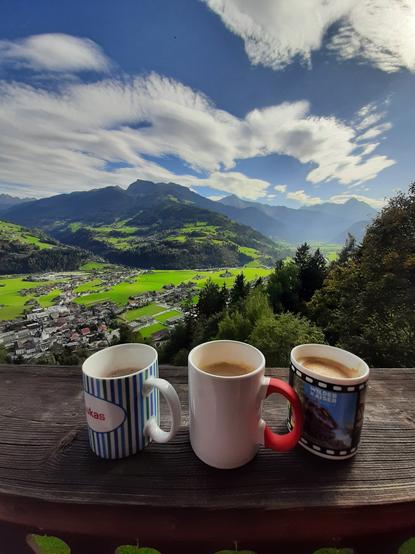 Auf einer Balkonbrüstung stehen drei Tassen Kaffee. Im Hintergrund blickt man ins Zillertal.