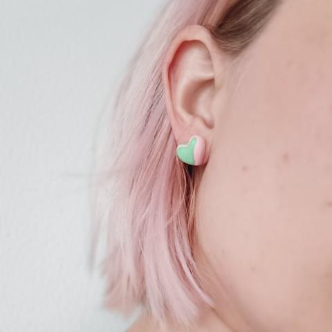 hartjes oorbellen van jesmonite in oor. Ze hebben een pastel roze met mint groen marmer effect
