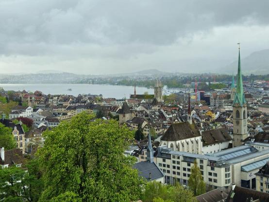 Foto mit Blick über die Stadt Zürich an einem Regentag. Im Hintergrund der Zürichsee und das Grossmünster.