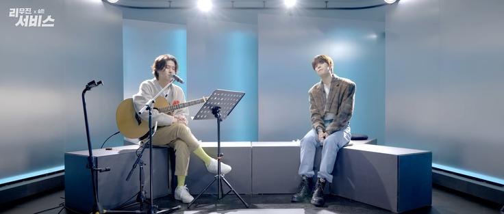 Lee Mujin with a guitar, and Seungmin with a microphone, on the set of Lee Mujin Service