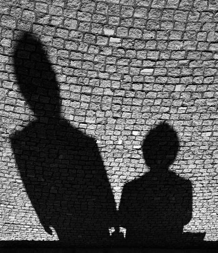 Shadows of two figures on a cobblestone surface, captured in black and white.