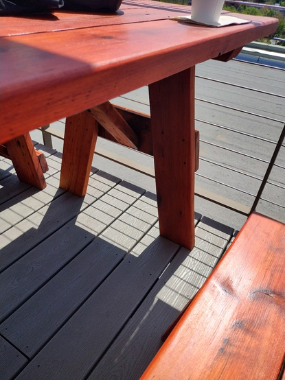 A gorgeously-designed picnic table of sold stained to be reddish wood on the outdoor balcony of Revolution Hall