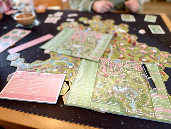 Das Kampagnenblatt von Dorfromantik: Sakura und ein voller Tisch bedeckt mit Plättchen aus dem Spiel.