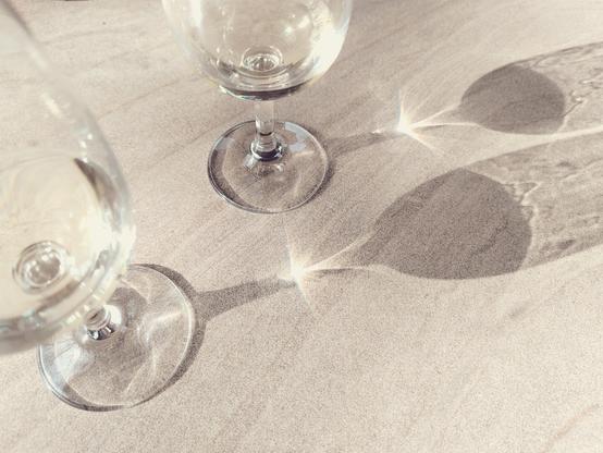 Two wine glasses on a table. They cast a shadow.