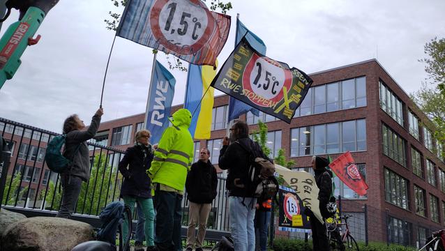 Wehende Fahnen und Demonstrant*innen vor einem Bürogebäude