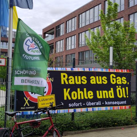 Banner und Fahne vor einem Zaun: raus aus Gas, Kohle und Öl! Christians for future.