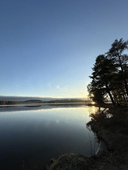 Sunset on lake Tuomionjärvi, almost mirror reflection, partly clear sky