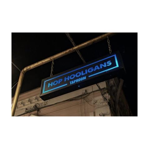 An illuminated sign advertising the Hop Hooligans tap room.