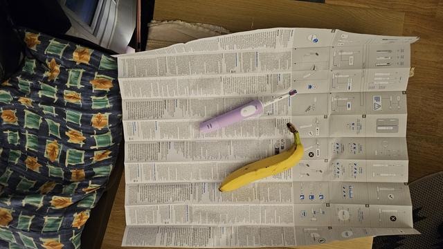 A white and purple electric toothbrush and a good-sized banana laying on the instructions for said toothbrush. 

A2 size, maybe. Massive road-map instructions.