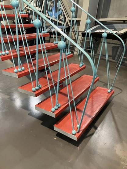 Stairs inside the Atomium, the steps are painted in red, the banister in light blue, with little spheres up and down.