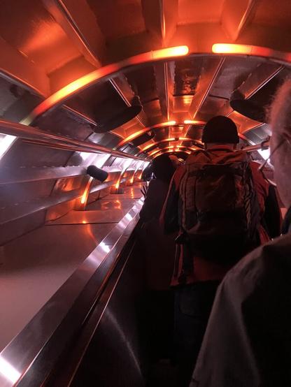 On an escalator inside the « arms » of the Atomium. They are illuminated with different flashy lights creating an effect of unreal.