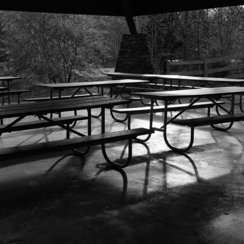 Picnic tables under a picnic shelter, the slant of the sunlight and the partial cover provides a good bit of contrast and shadow.