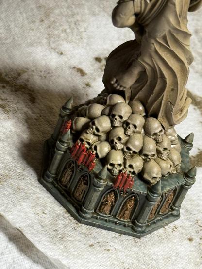A detail of a 28mm-scale statue plinth, with skulls stacked at the base