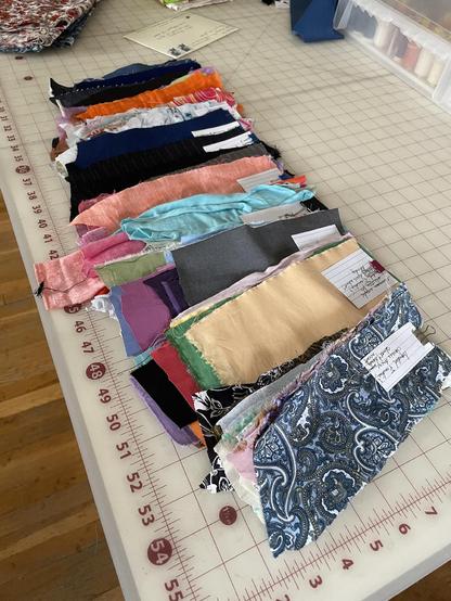 A spread of solid and print fwbric swatches in every color under the rainbow. All prints are either floral or paisley. The swatches are grouped into sets and clipped together at the top.