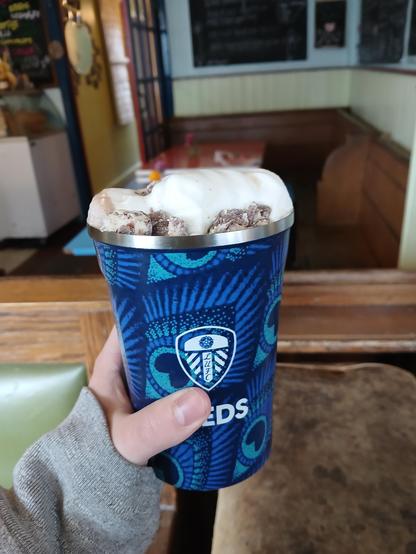 A white hand holding a leeds united flask with cream and mini eggs coming out the top