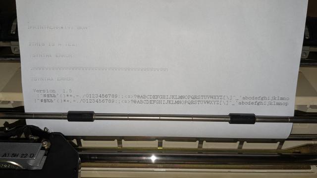 Sheet of white paper in a dot matrix printer. On top of the sheet there are multiple lines of very faint text, then two lines of much darker, clearer characters.