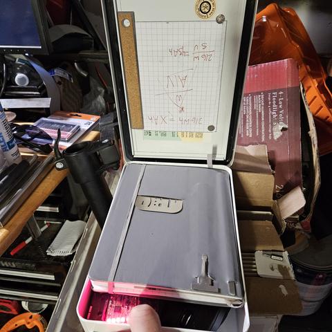 a punk pc built out of a first aid kit. there is a notebook on top and a finger pressing a button, illuminating 4 LEDs.