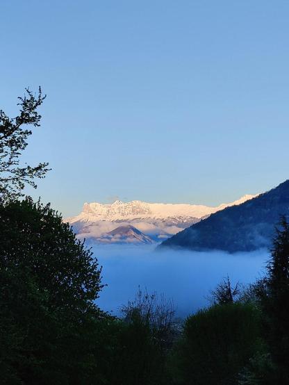 Lever de soleil sur le Vercors sous la neige, sous un grand ciel bleu, au-dessus d'une mer de nuages.