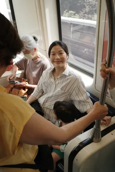 A scene in a Taipei MRT train: a young woman sitting is looking at the camera, while hugging her daughter