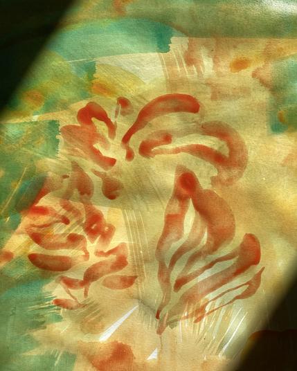 A section of a painting sketch on paper that is highlighted by a beam of sunshine. The sketch is a jumble of thinly painted, broad brushstrokes of pale yellow and pthalo green on a white background. Over the wash of yellow and green is a squiggly burst of orange brushstrokes, like loose flames.