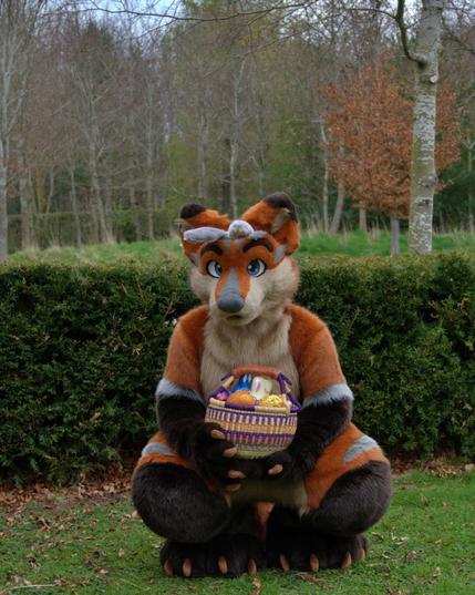 Terrence is crouching in front of a hedge, wearing bunny ears and holding a basket of easter eggs