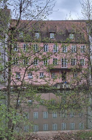 Ein Haus mit vielen Fenstern an der Pegnitz in Nürnberg spiegelt sich im Fluss.