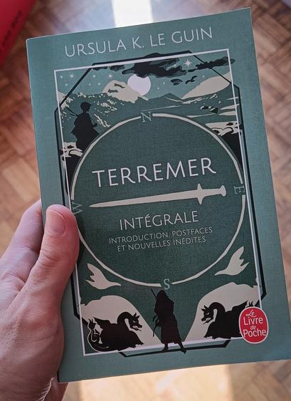 Photo du livre « Terremer — Intégrale » d'Ursula K. Le Guin, édition Le Livre de Poche.

L'illustration, avec une palette épurée présente uniquement des nuances de bleu-vert et du noir, est en 3 parties : en haut, on voit la silouhette d'un jeune homme en noir, devant un paysage montagneux, au-dessus duquel on perçoit un ciel étoilé et la pleine lune ; en bas, une silouhette humaine est représentée au milieu de 2 silouhettes de dragons positionnées de manière symétrique ; au centre, un cercle annoté des 4 points cardinaux comme une boussole sépare les 2 autres parties et laisse de la place pour le titre du livre, une épée est dessinée horizontalement dans ce cercle, pointe vers l'Ouest, et sépare les 2 parties du titre : « Terremer » et « Intégrale : Introduction, postfaces et nouvelles inédites ».
