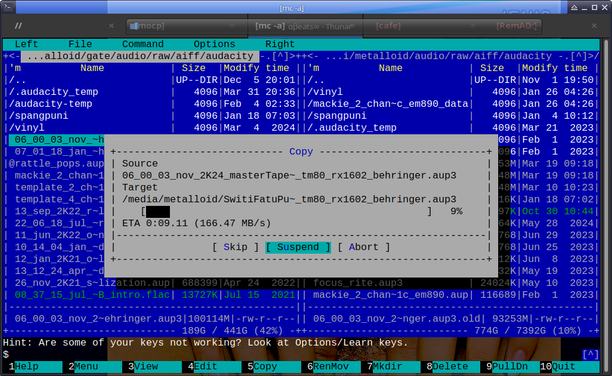 The screencap shows a computer screen displaying a file manager interface, specifically the Midnight Commander (mc) software. The interface is split into two panes, with the left pane showing a directory path starting with "/.../audacity_temp" and the right pane showing a directory path starting with "/.../metalloid/audio/raw/audacity". The left pane lists various files and directories with their names, sizes, and modification times, while the right pane shows a file transfer operation in progress. The file being copied is "06_00_03_nov_2K24_masterTape_t80_rx1602_behringer.aup3" from the source directory to the target directory "/media/metalloid/SwiftFatu_Pu_t80_rx1602_behringer.aup3". The transfer is 9% complete with an estimated time of arrival (ETA) of 0:09.11 at a speed of 166.47 MB/s. The interface includes buttons for "Skip," "Suspend," and "Abort" the operation. The bottom of the screen shows a status bar with various options and a hint about key bindings. The overall color scheme is blue and black, typical of the Midnight Commander software.