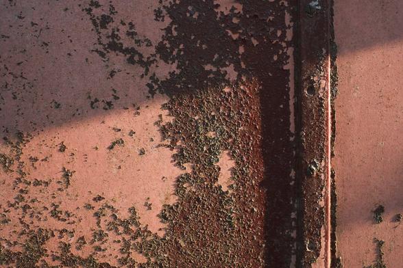 Evening sun catching the texture of old fading and peeling paint on a coach body