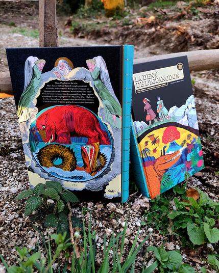 Photo de la 4 de couverture de la BD "La dent de l'iguanodon" de Lisa Lugrin, Clément Xavier et Pol Cherici, sur un sol caillouteux dans lequel est planté une pioche (subtile allusion à la couverture et à la vie de ces paléontologues du XIXeme) - on voit un autre exemplaire de la BD deriière, qui laisse voir la couverture