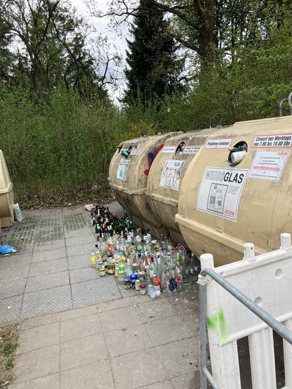 Foto von Altglas Containern, vor ihnen steht eine große Menge Flaschen auf dem Boden