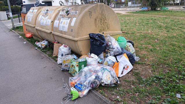 Wertstofinsel in München mit überfüllten Containern und Abfallhaufen daneben